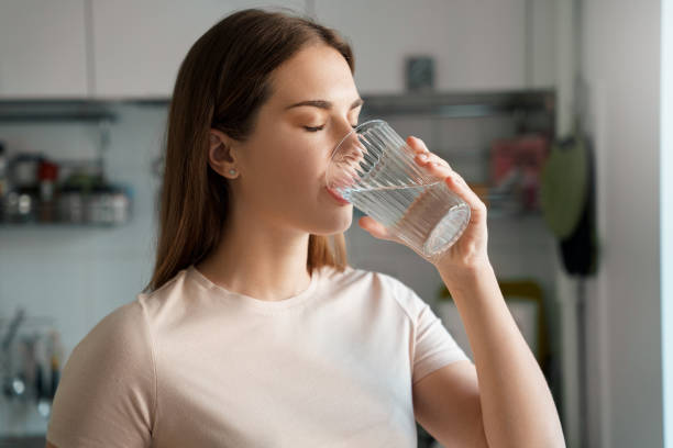 Mujer joven bebiendo agua filtrada en casa